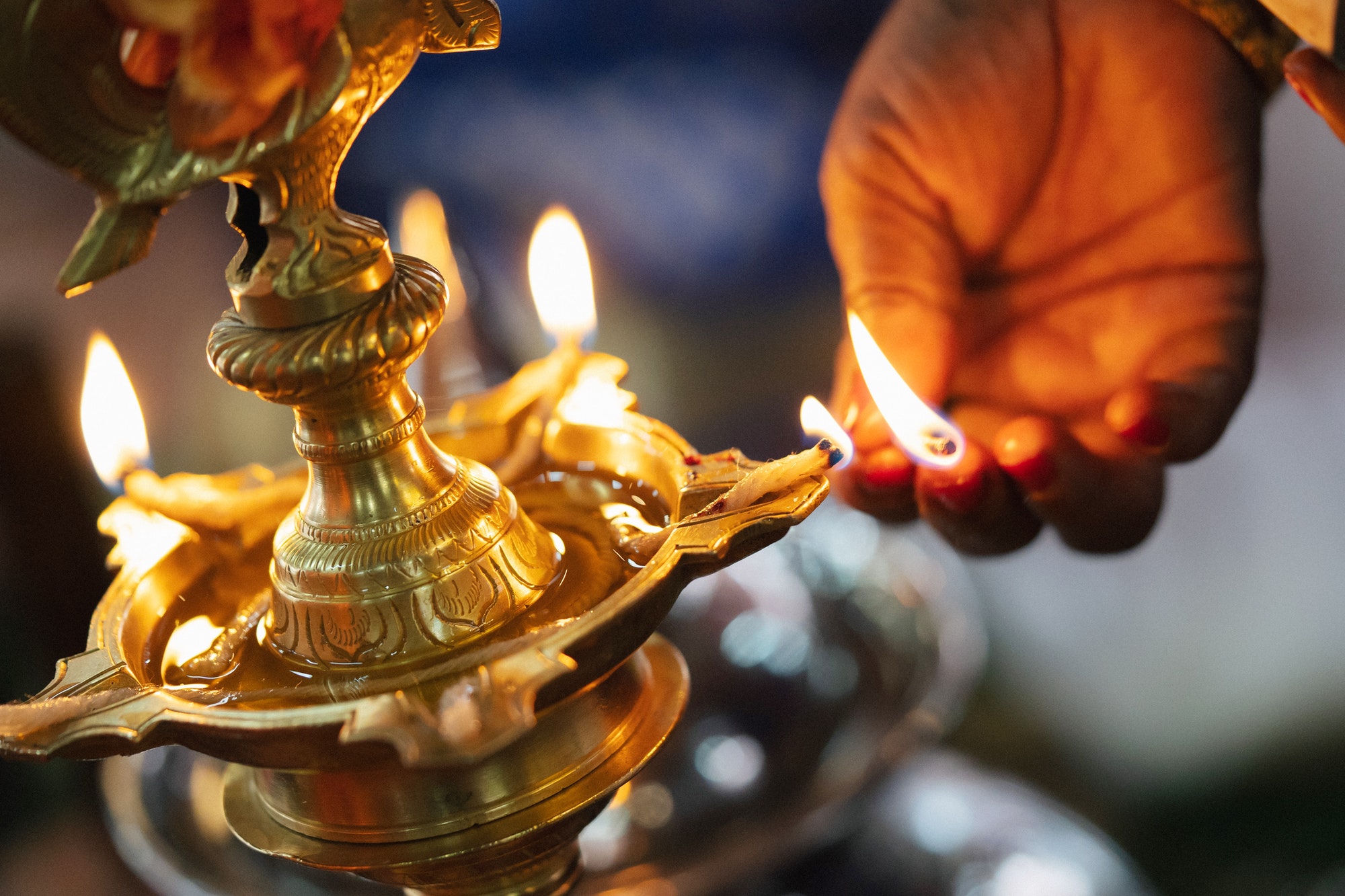 Indian women hand lighting up the lid of the traditional brass oil lamp in the south Indian wedding